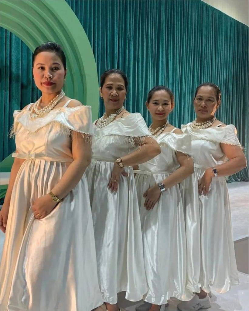 a group of women in white dresses at Arabic Coffee shop who serve the clients with love and care while presenting a cup Arabic Coffee